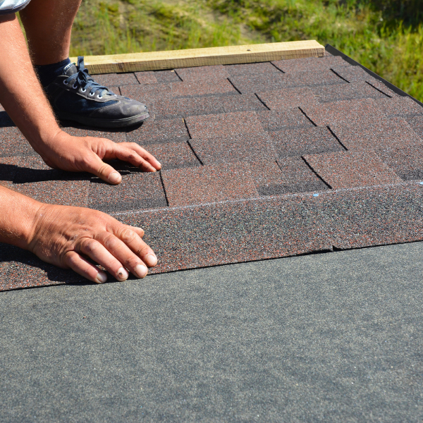 Roofing Welland - Roofing Solutions Pros & Cons Of Shingle Roofing - a roofer's hand on asphalt shingle roof