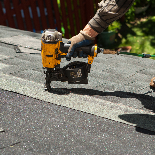 Roofing Contractor in Welland How to Get the Best Value For Your Money - a roofer's hand attaching shingles with a nail gun