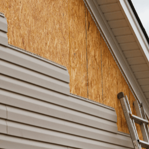 vinyl siding contractors near me - Why Choose Vinyl Siding For Your Home - beige vinyl siding being installed on the side of a house