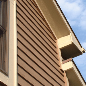roofing and siding contractors near me - the side of a house showing tan vertical siding and roof details